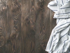 View from above on brown wooden table with linen kitchen towel or textile napkin. Blue tablecloth