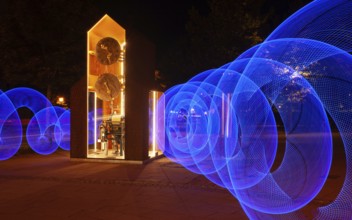 Blue light circles created with LED lights encircle an artistic large clock, Lightpaniting,