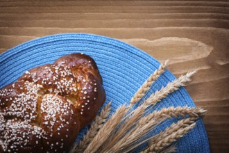 Sweet roll wheat rye ears with blue wattled cover on wooden board food and drink concept