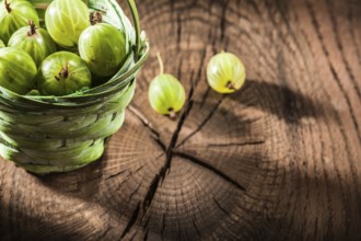 Fresh gooseberries in basket on vintage wooden board