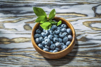 Ripe huckleberries in wooden bowl top view