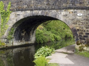 An old stone bridge crossing the rochdale canal at mytholmroyd west yorkshire with a waterside