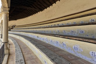 Bullring of Ronda, Plaza de Toros, Numbered rows of seats in an arena with old-style wood and stone