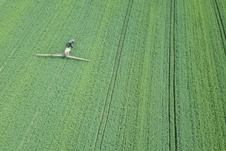 Aerial view Farm machinery spraying chemicals on the large green field, agricultural spring