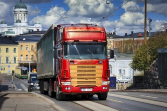 Red and gold 4-series Scania truck pulling semi trailer to Katajanokka Harbour. On the background