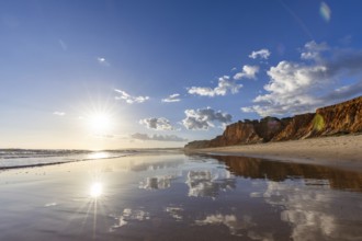 The golden sandy beach of Praia da Falésia, crystal clear sea water at low tide with the reflection