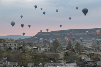 A picture of hot air balloons flying over the Goreme Historical National Park and the town of