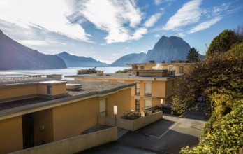 Amazing view of 4-story apartment buildings on the shores of Lake Lugano and a park on the coast