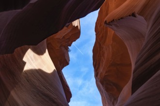 A picture of the rock formations of the Lower Antelope Canyon, while a plane is flying in the blue