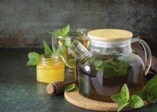 Therapeutic herbal green tea. Hot tea with honey mints in a glass teapot on a stone table. Copy