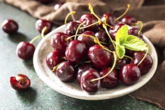 Ripe organic berry. Fresh Red sweet cherry on plate on a dark stone tabletop