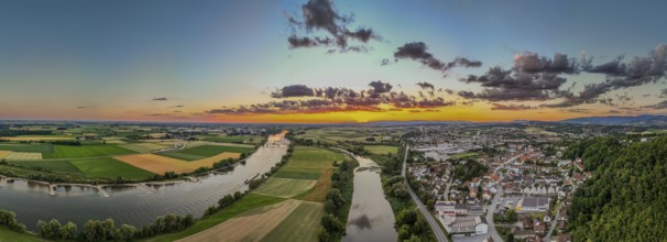 The sunset bathes the landscape in warm light, while the Danube flows calmly and the town of Bogen