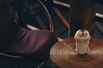 A cozy cafe setting with an iced coffee on a round rattan table and chair