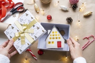 Key to house with keychain on cozy home in gift box with Christmas decor packaging. Pack present