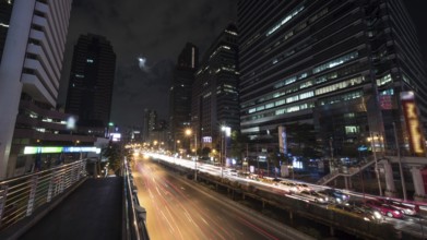 Timelapse shot of night Bangkok street. Intense transport traffic on the road with highrise