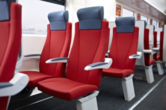 An interior view of a modern high speed train. Red chairs