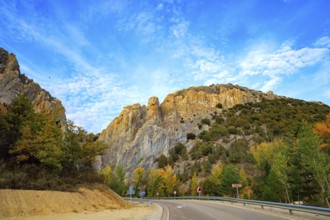 The trip to Spain. Asphalt highway passes among steep cliffs. The sky is covered with light clouds