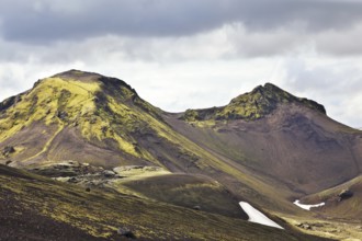 National Park Landmannalaugar in July. Green and pink mountain slopes and snowy white residues from