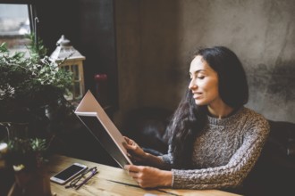 Young business girl studying the menu in restaurant decorated with Christmas decor.sits near the
