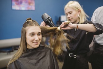 Portrait of happy woman at the hair salon. Professional hair styling concept. Hairdresser drying