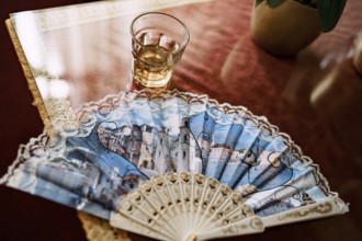 Hand-held fan and a glass of cognac on the table.