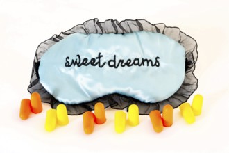 Sleeping mask with orange and yellow ear plugs isolated on a white background. Sweet dreams. Studio