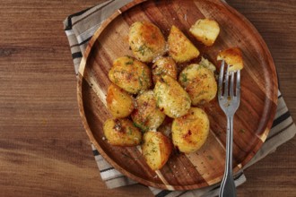 Half-eaten fried new potatoes, with butter and dill, on a wooden plate, with a fork, at home,