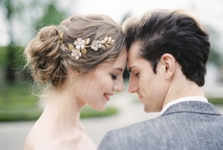 Smiling bride touches groom forehead with her forehead. Portrait.