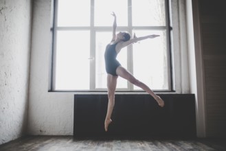 Plasticity slim woman dancing near window. Professional dancer enjoy dance. Lady Dancer Training