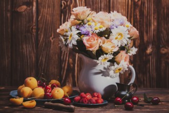 Summer still life with peaches, raspberries, cherries and flowers on a wooden table