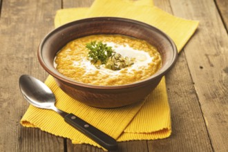 Pumpkin soup in clay bowl with spoon on the table