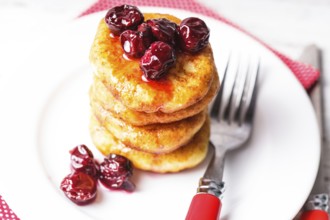 Cheese pancakes with cherry jam on the plate