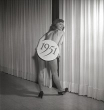 Ballet girl in the 1950s. A young woman on stage holding a sign with the year 1951 printed on it.