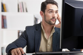Surprised man looking at a computer screen, thinking about the job at hand