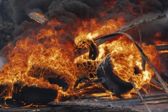 Burning automobile tires, strong flame of red fire and clouds of black fumes in sky. Selective
