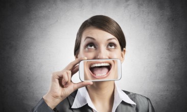 Portrait of young woman covering her mouth with smartphone. Businesswoman showing mobile phone with