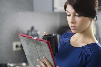 Portrait of young attractive caucasian brunette housewife at kitchen. Morning with cup of coffee