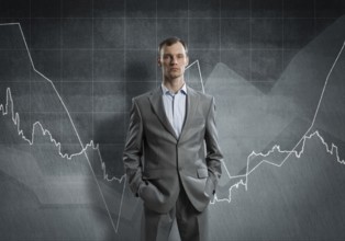 Businessman with arms in pockets and growing graphs on chalkboard