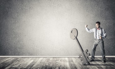 Determined businessman in concrete interior breaking with fist stone key figure