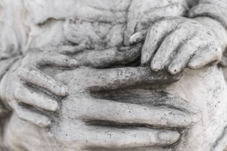 Detail of a marble statue with hands of child and woman together