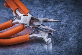 Set of insulated electric pliers nippers on scratched metallic background
