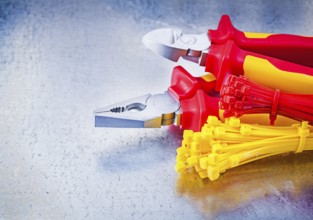 Nippers pliers self-locking cable ties on metallic background construction concept
