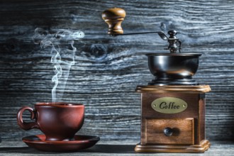Vintage wooden coffee mill and brown cup with steam