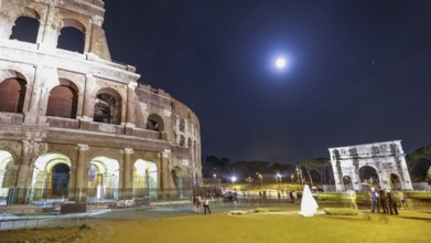 Roman Colosseum and Constantine Arch by night with tourists and photographers with a bride for