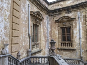 Weathered walls and ornate architectural details with classical windows and stone railing, Villa