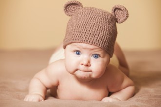 Adorable baby in bear hat lying on the bed