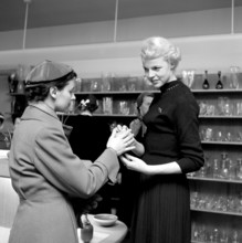 Shopping in the 1950s. A young woman in a store where a sales woman is presenting some of the