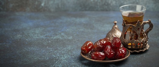 Breaking fasting with dried dates during Ramadan Kareem, Iftar meal with dates and Arab tea in
