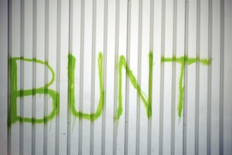 The detail of a corrugated iron façade colourfully painted with the slogan