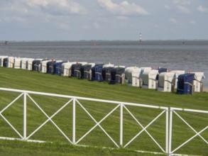 Row of beach chairs along a fence overlooking the sea, wilhelmshaven, germany